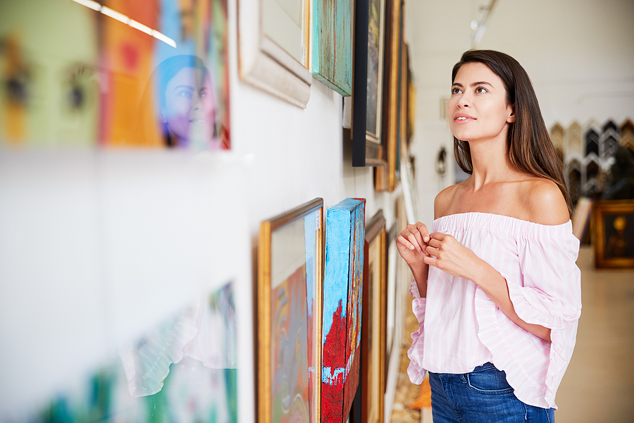 Woman Looking At Paintings In Art Gallery